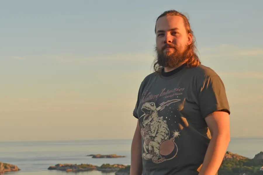 En mann med skjegg stående ved vannet